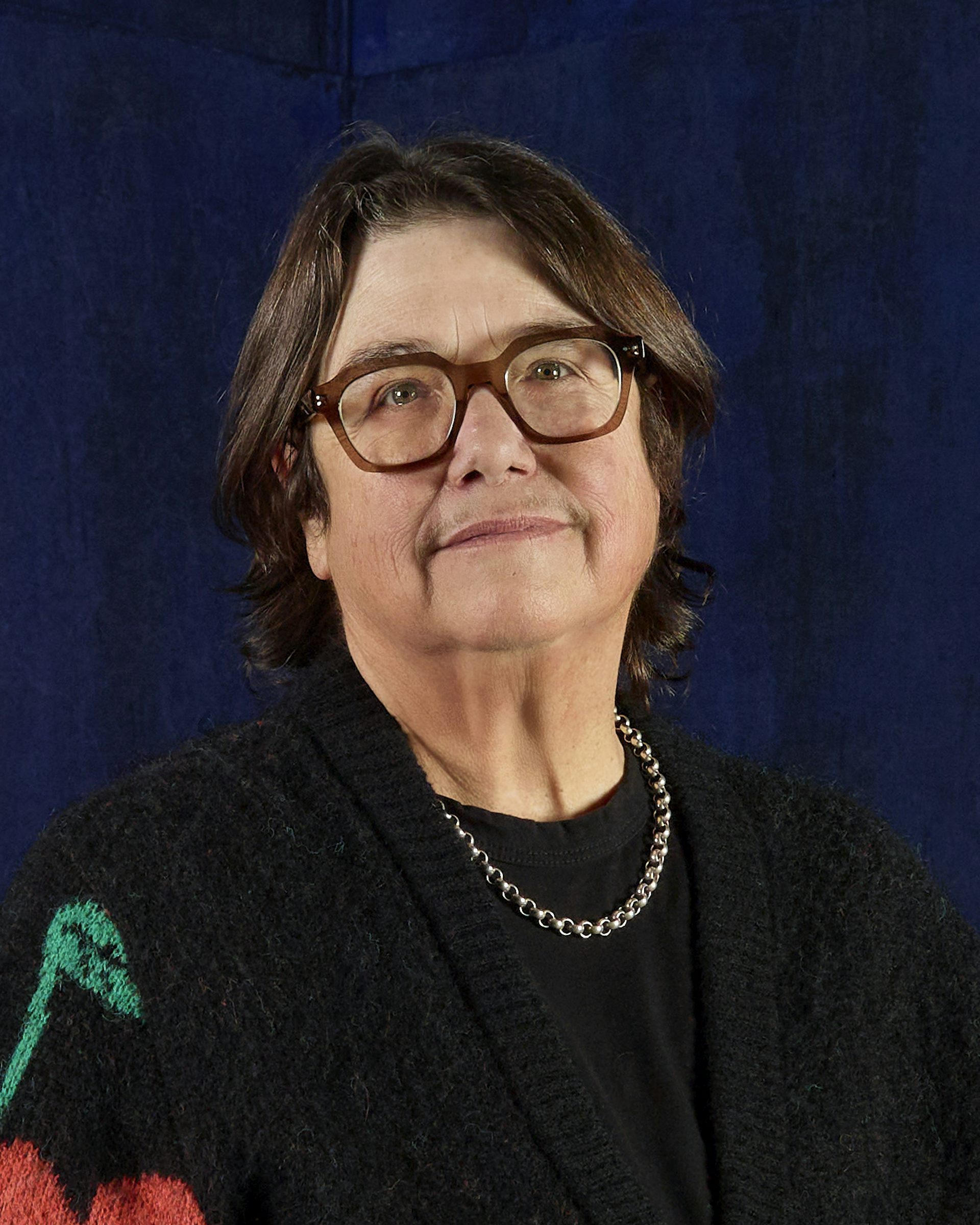 A middle-aged woman in a black jumper smiling faintly at the camera.