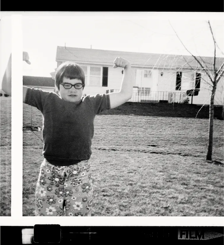 A black and white old fashioned images of a child in a bowl cut with specs and