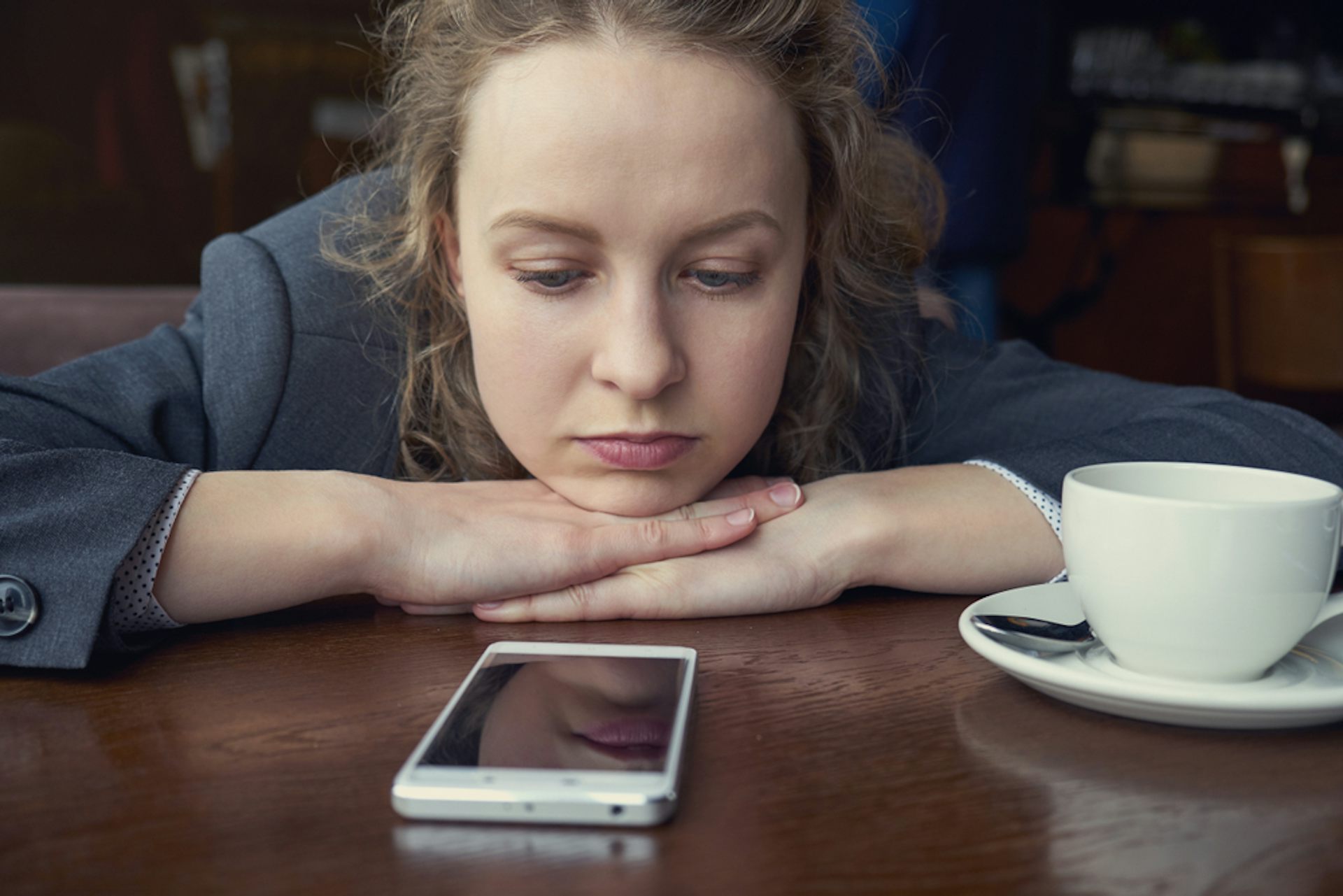 Une jeune femme regarde son téléphone fixement. 