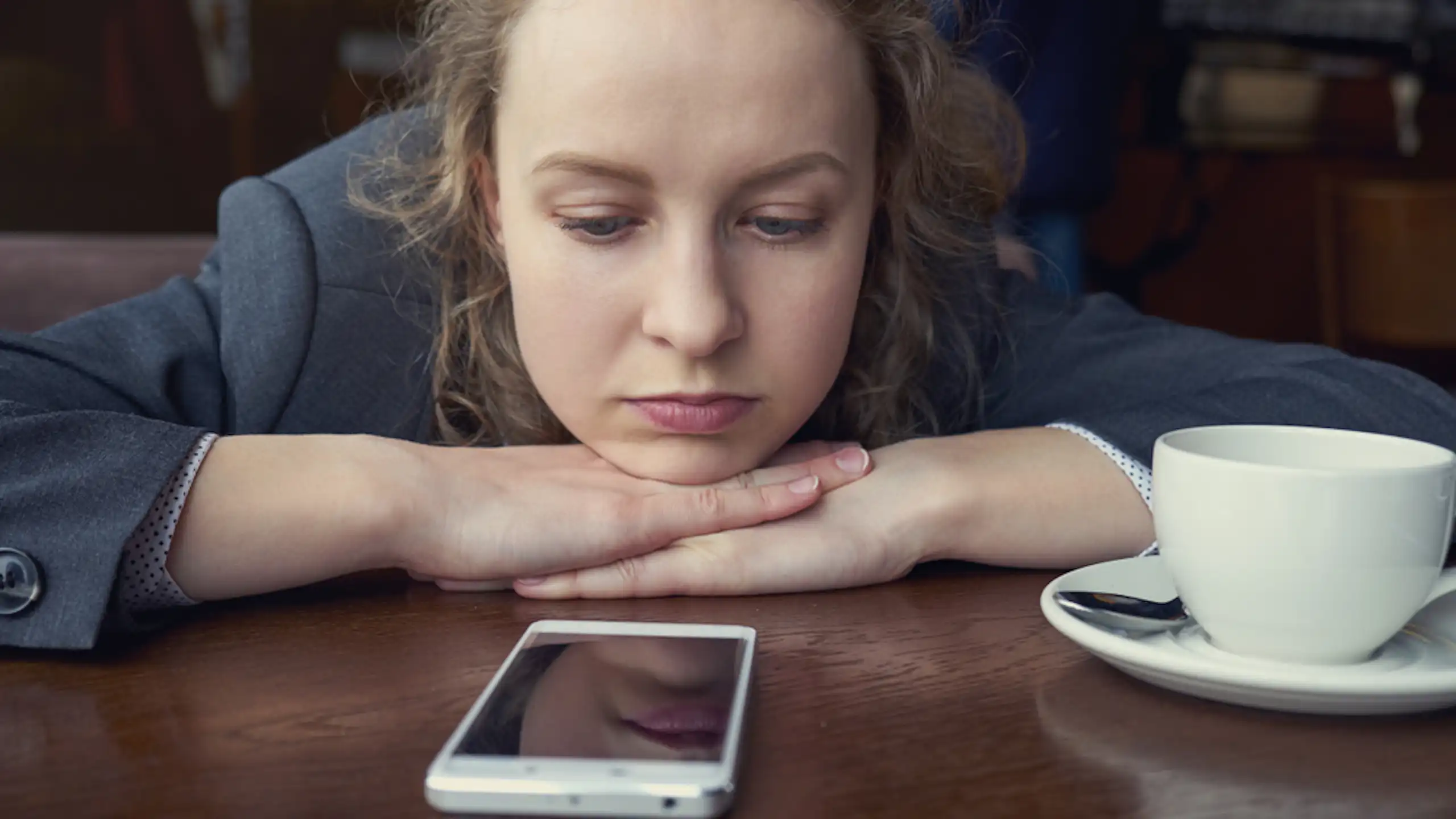 Une jeune femme regarde son téléphone fixement.