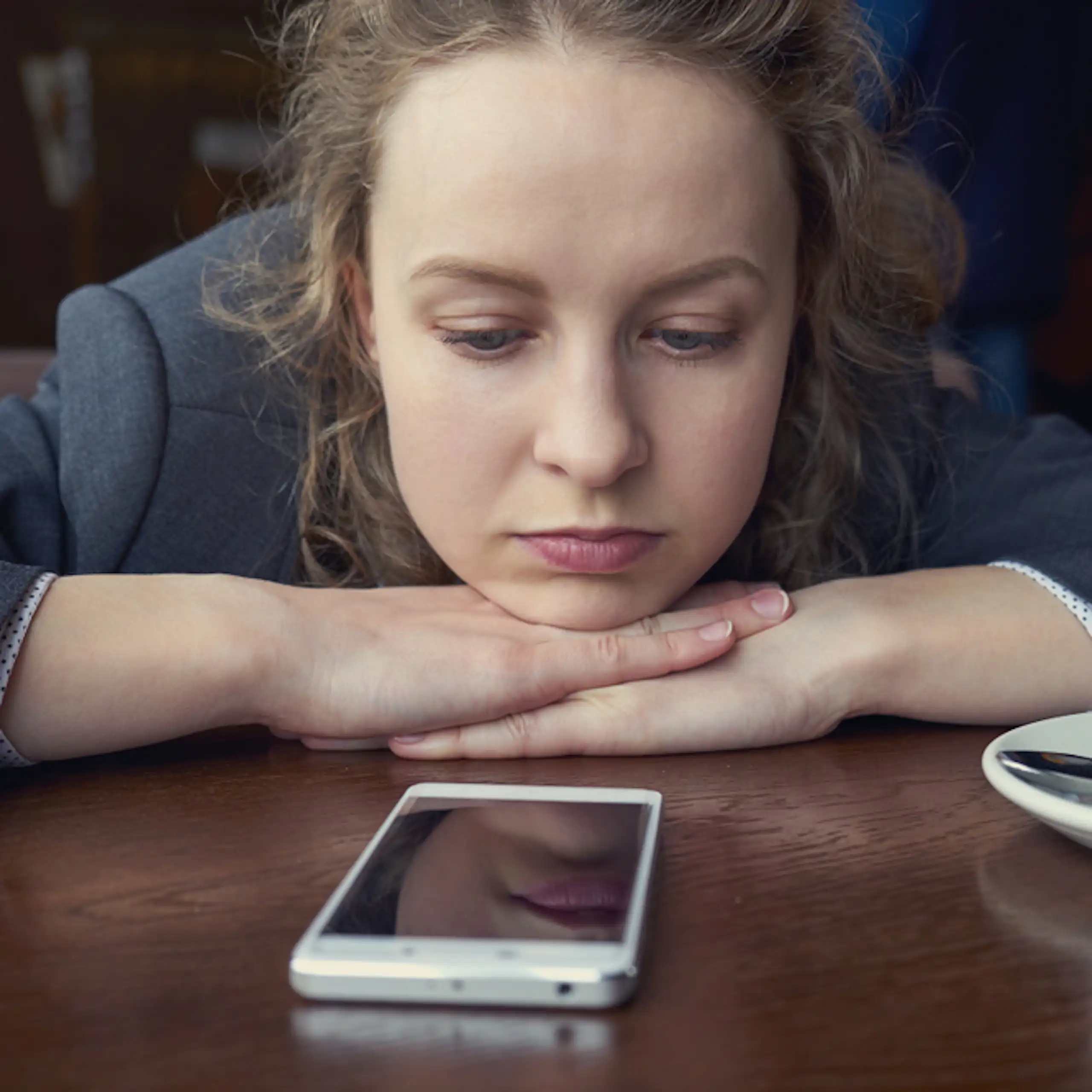 Une jeune femme regarde son téléphone fixement.