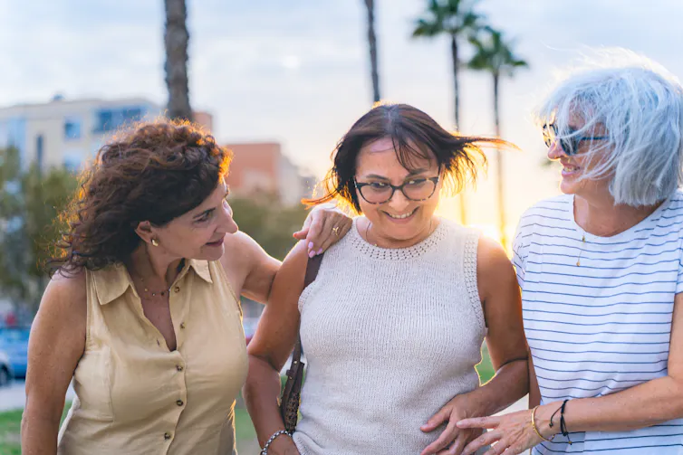 three smiling older women on a walk together