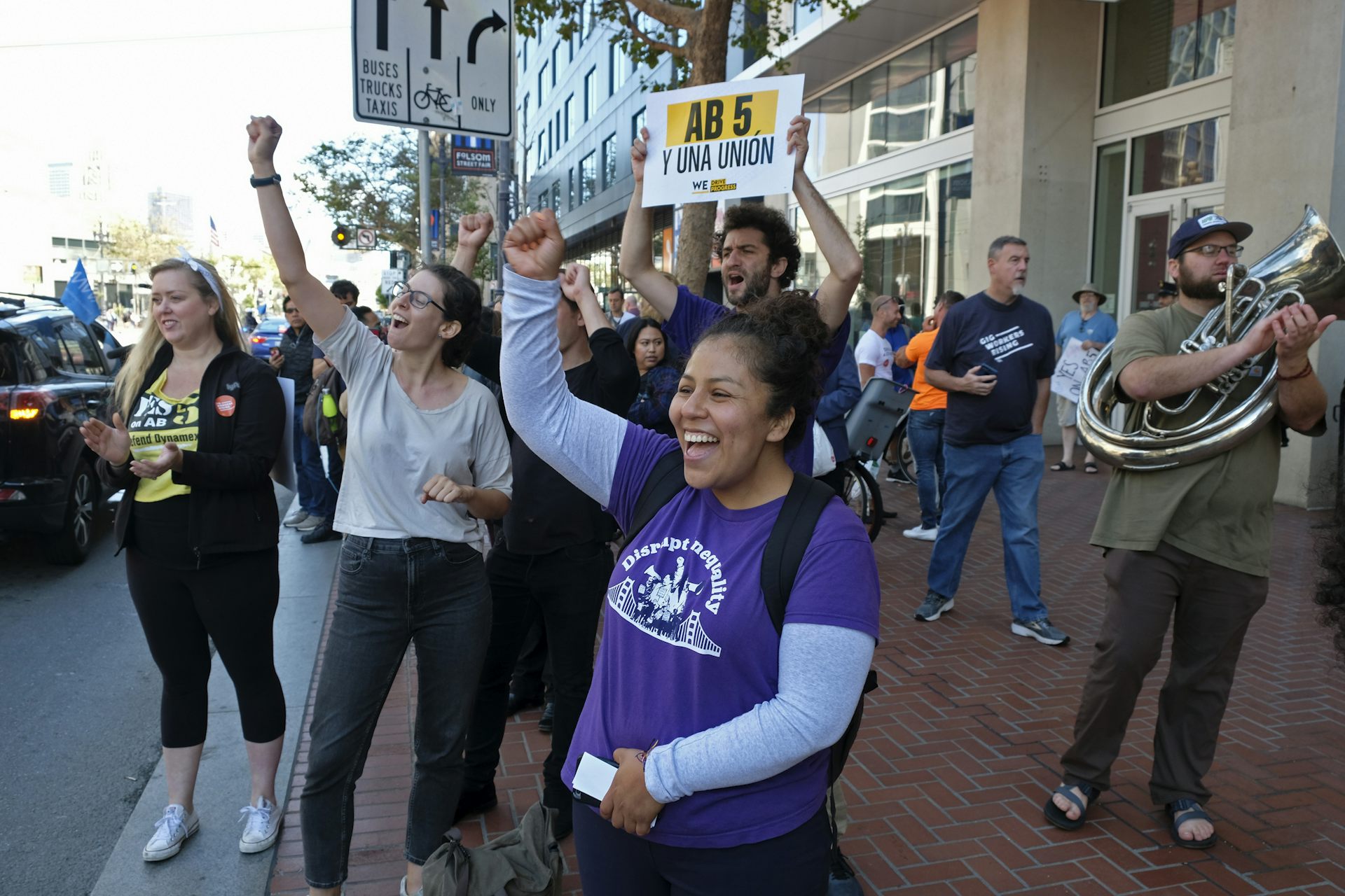 People cheer at honking drivers circling the headquarters of Uber in San Francisco during a protest calling for better worker protections.