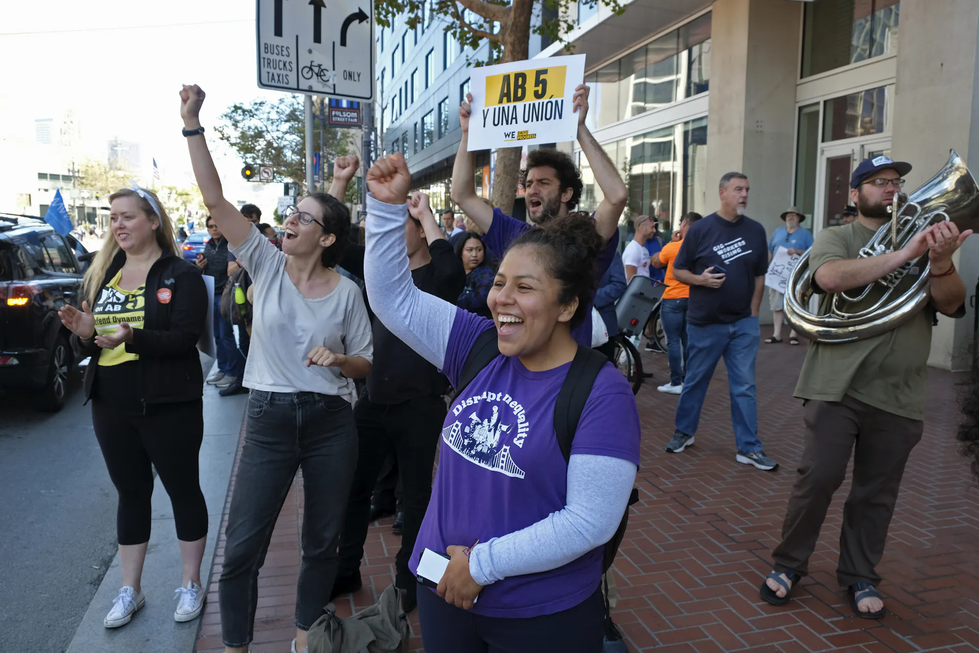 People cheer at honking drivers circling the headquarters of Uber in San Francisco during a protest calling for better worker protections.