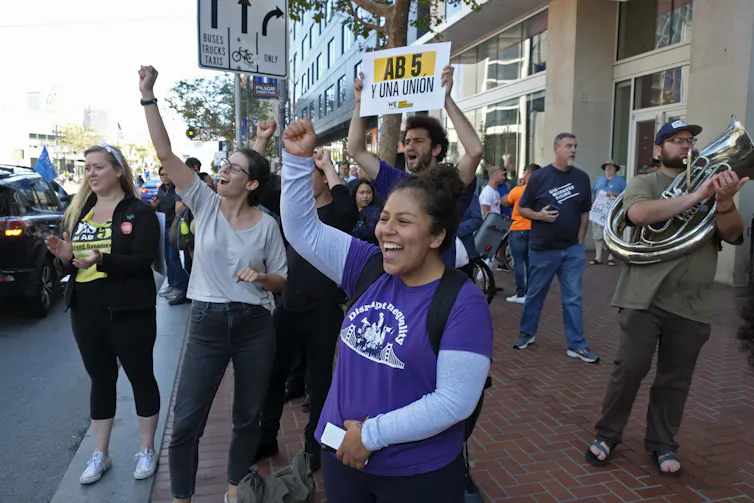 People cheer at honking drivers circling the headquarters of Uber in San Francisco during a protest calling for better worker protections.
