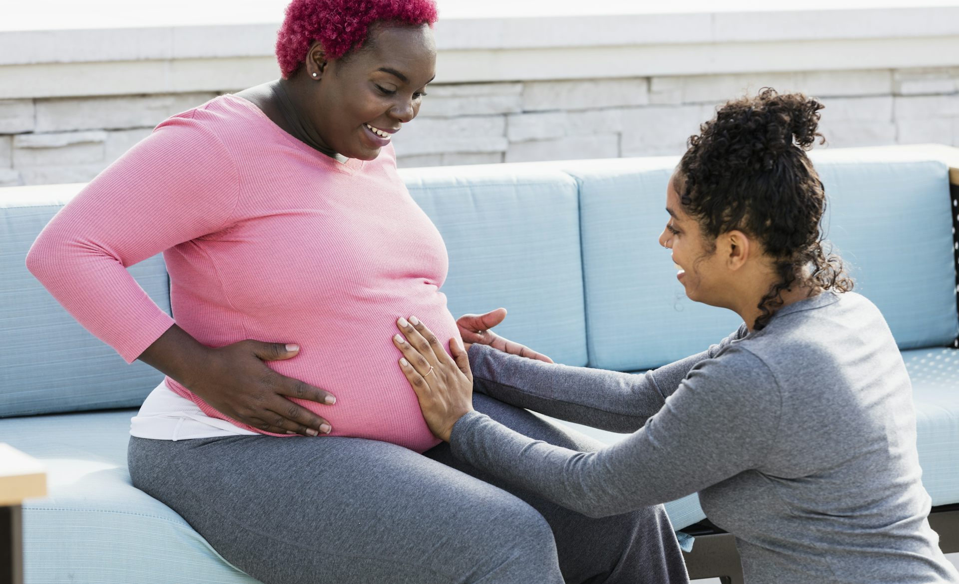 A doula touches a pregnant woman's belly