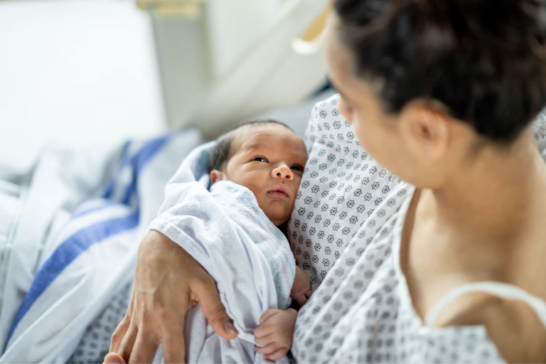Woman in hospital bed holding newborn.