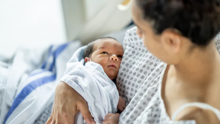 Woman in hospital bed holding newborn.