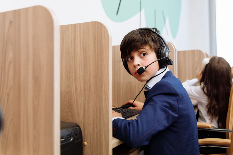 A young child with a headset on works at a keyboard.