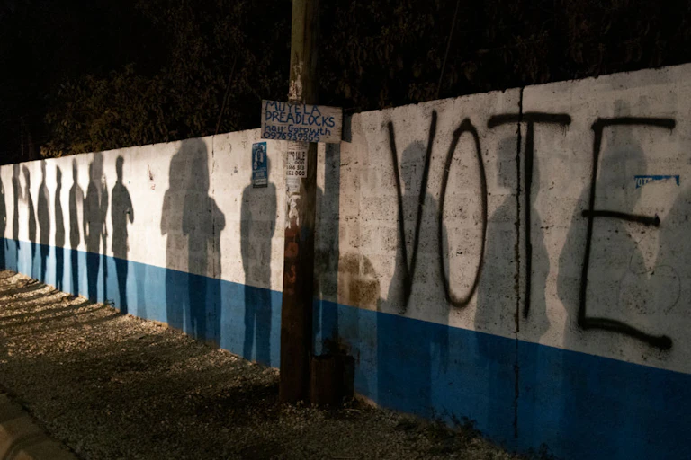 Shadows of people on a wall, with the word "vote"