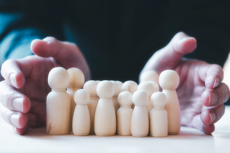 Un conjunto de figuras de madera sobre una mesa entre dos manos