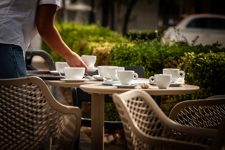 Un camarero recoge una taza de una mesa en una terraza