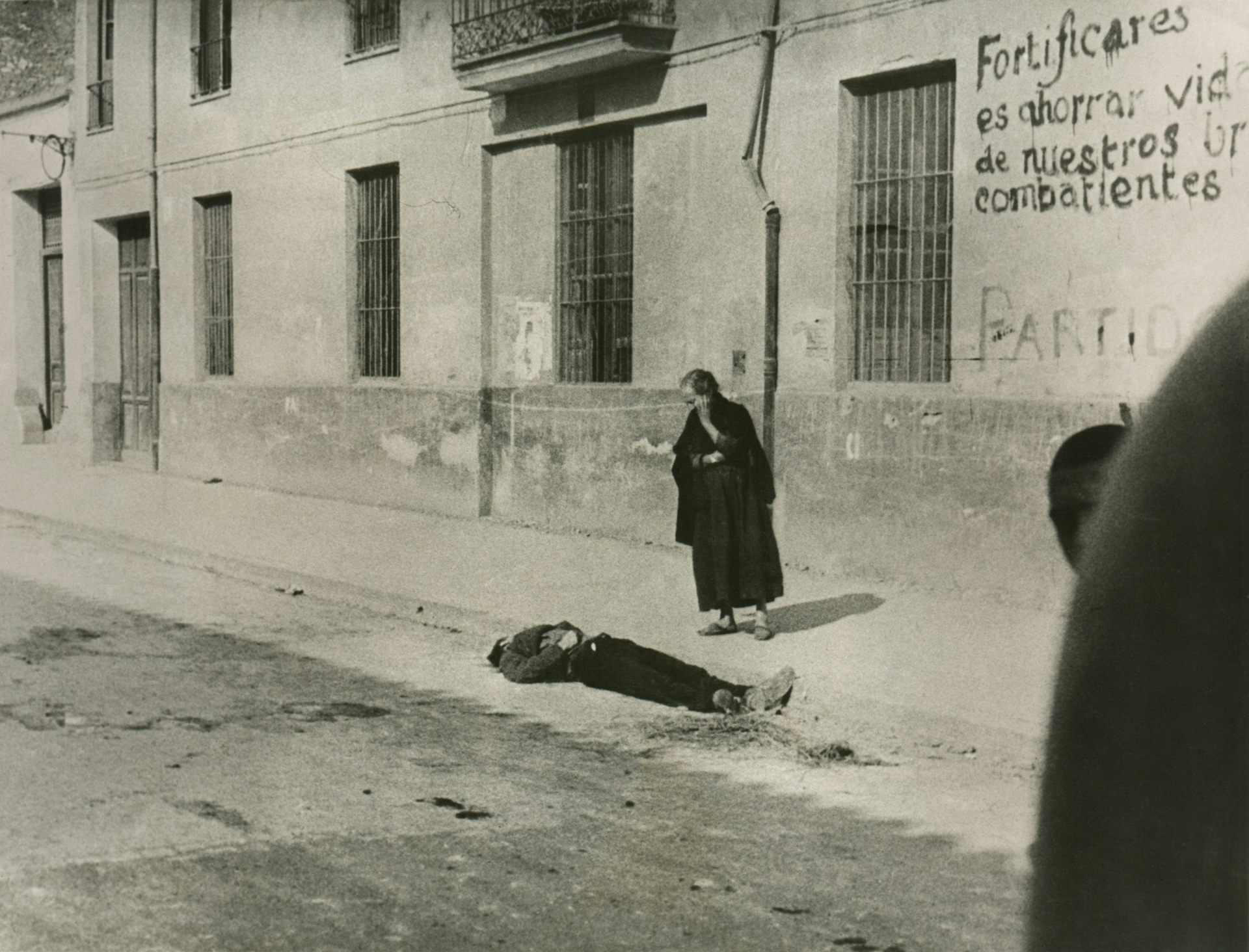 Una madre contempla el cadáver de su hijo en una calle de Castellón. Foto en blanco y negro.
