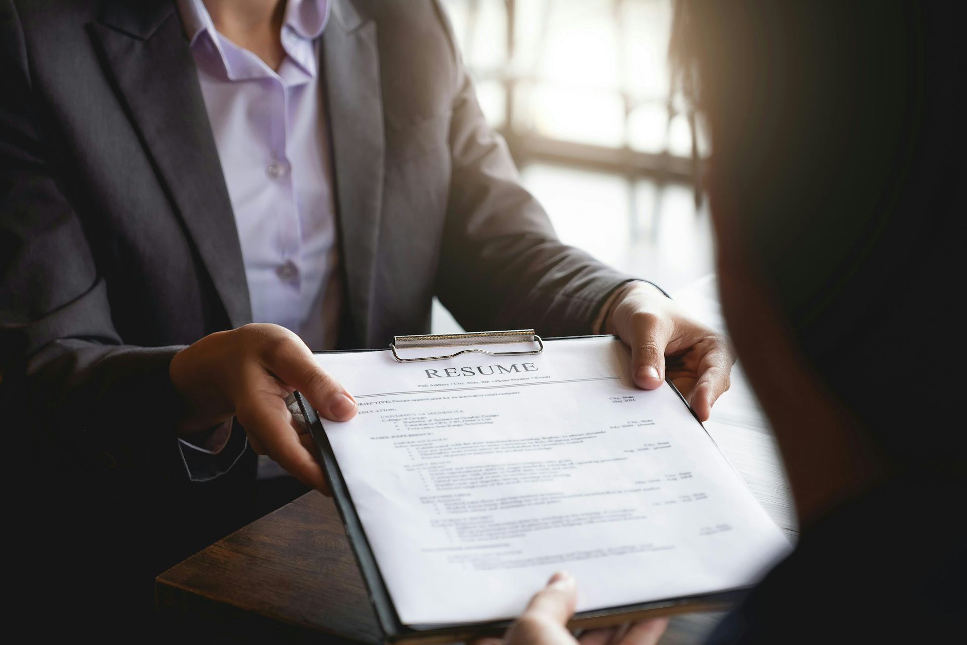 A person hands a resume to a manager