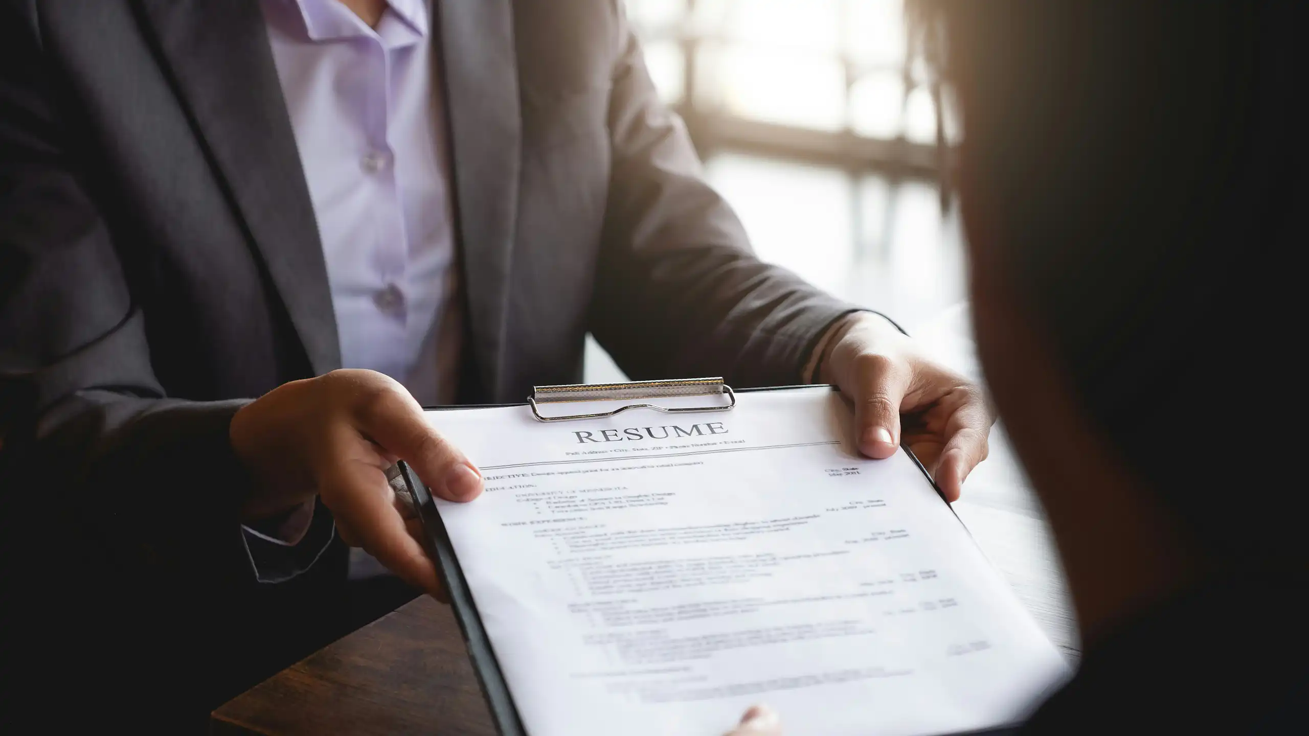 A person hands a resume to a manager