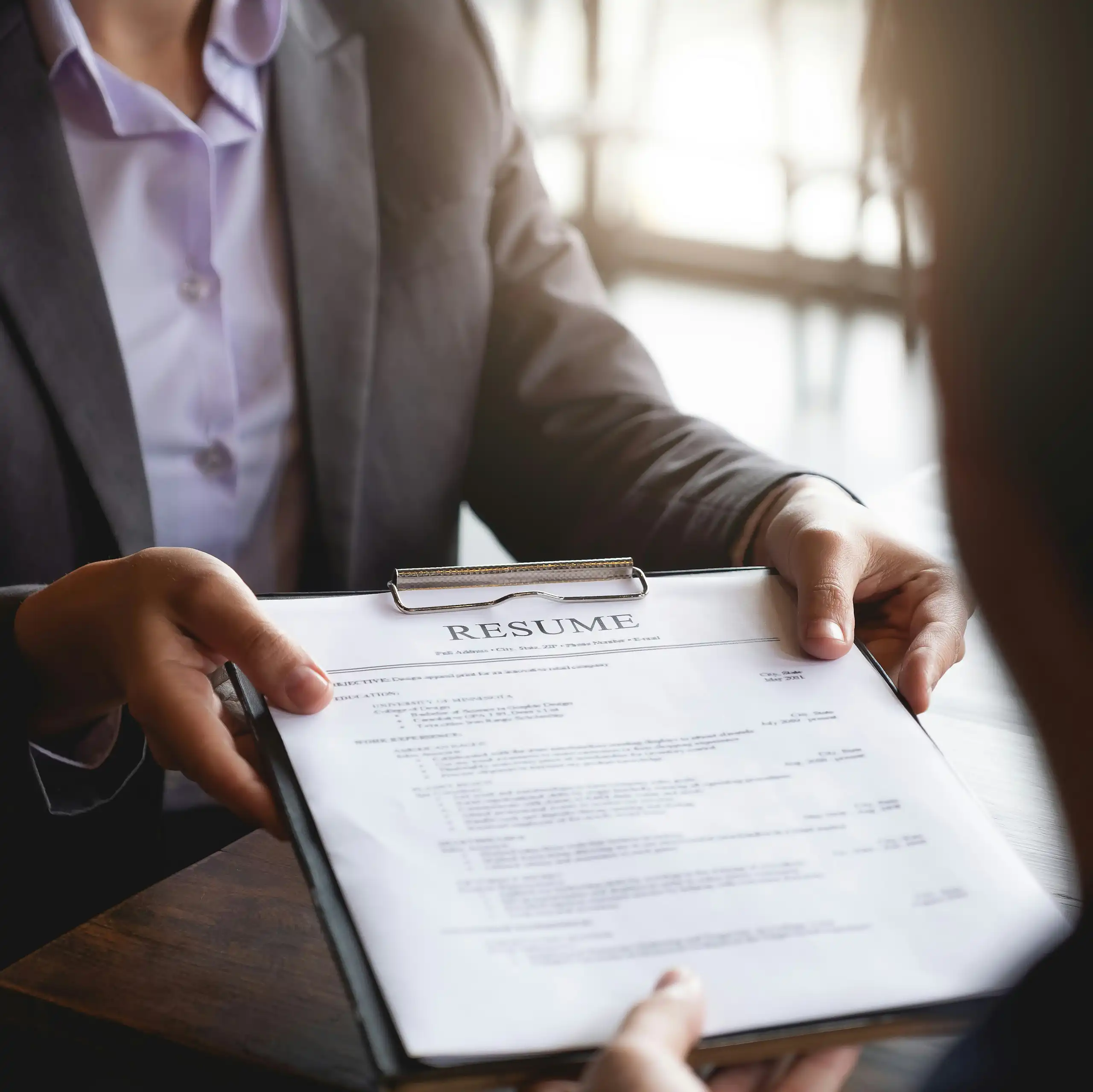 A person hands a resume to a manager