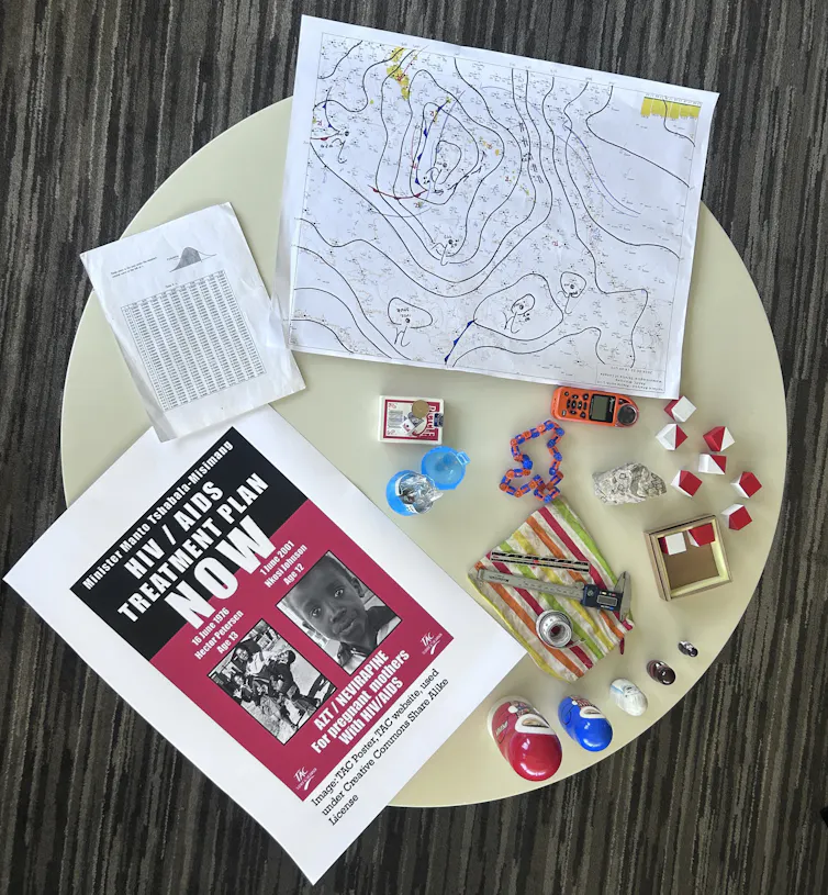 A table with a variety of objects: a map, a pamphlet, a statistical table, a coin, a deck of cards, two-colored dice and more.