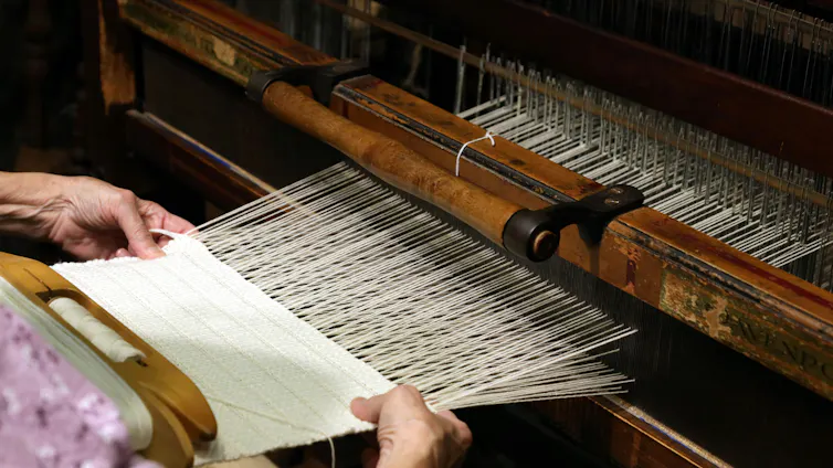Close up of someone's hands as they weave on a loom