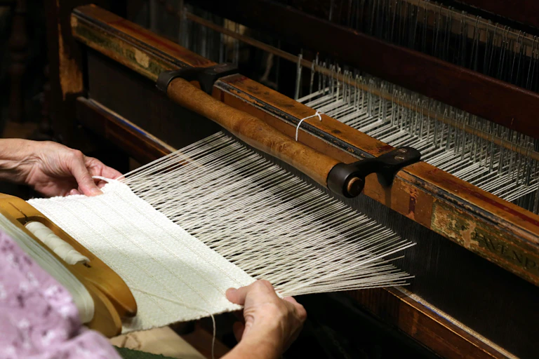 Close up of someone's hands as they weave on a loom