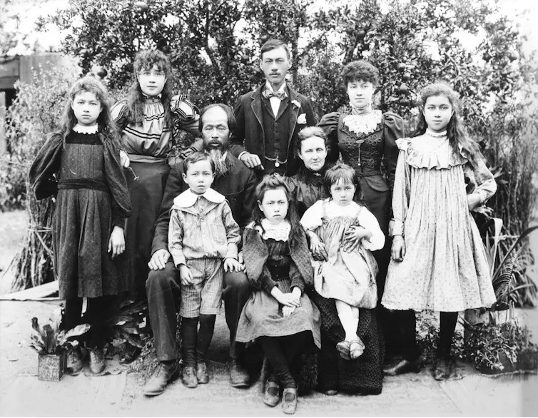 A black and white photograph of a large family, well dressed in Victorian clothes