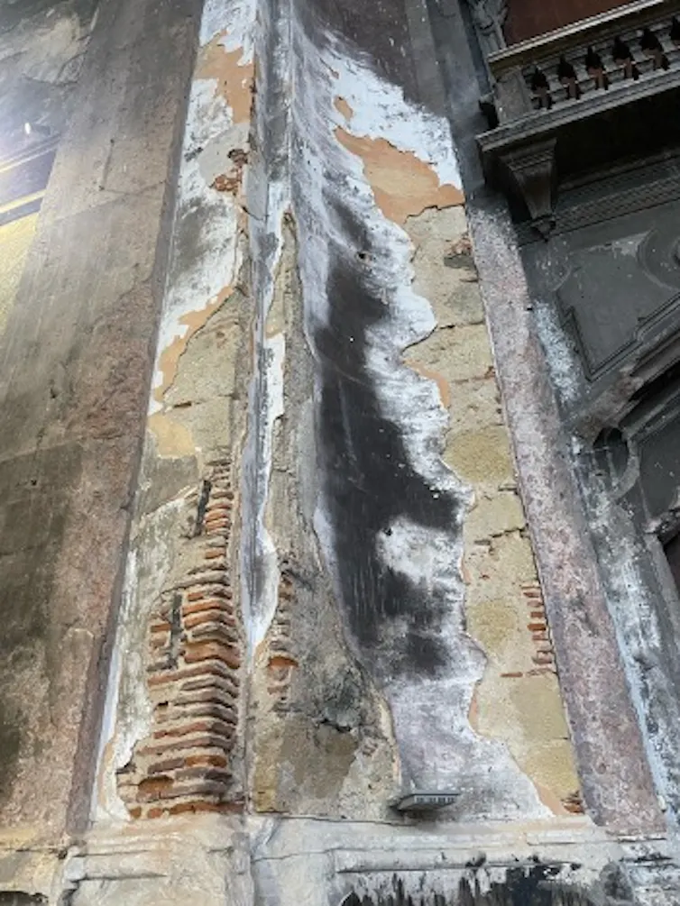 A photo shows a damaged church fascade with brick showing through.