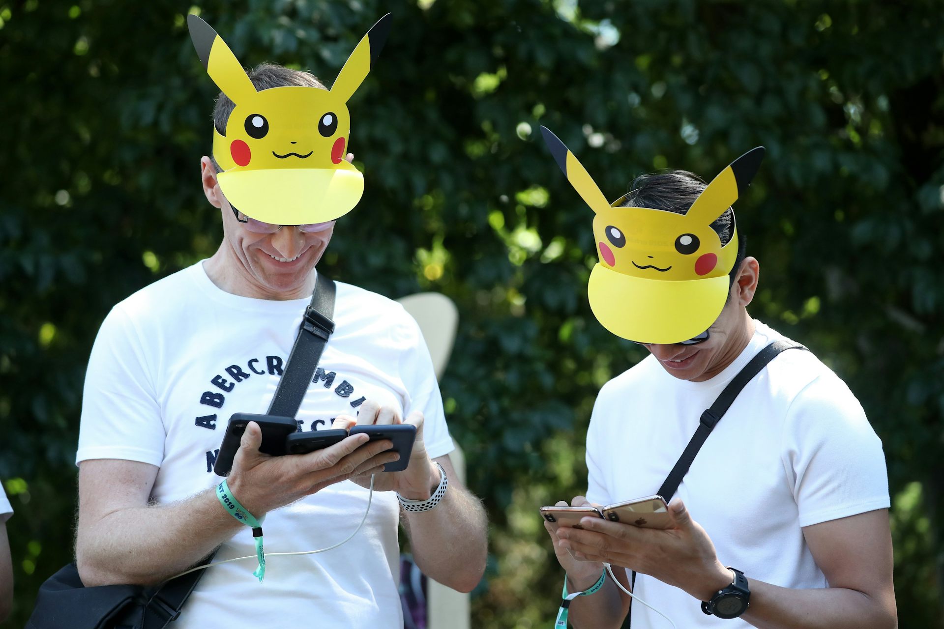 People play the Pokemon Go game on their smartphones, wearing Pikachu hats.