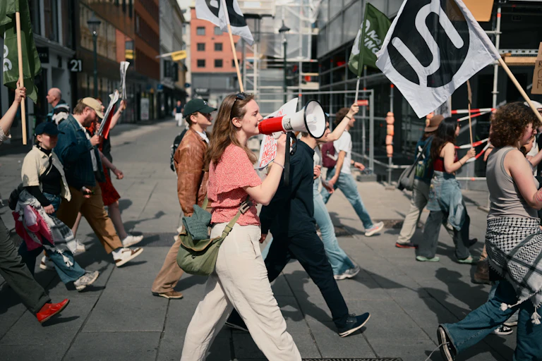 Protesters carrying political banners march through the Youngstorget public square in Oslo.