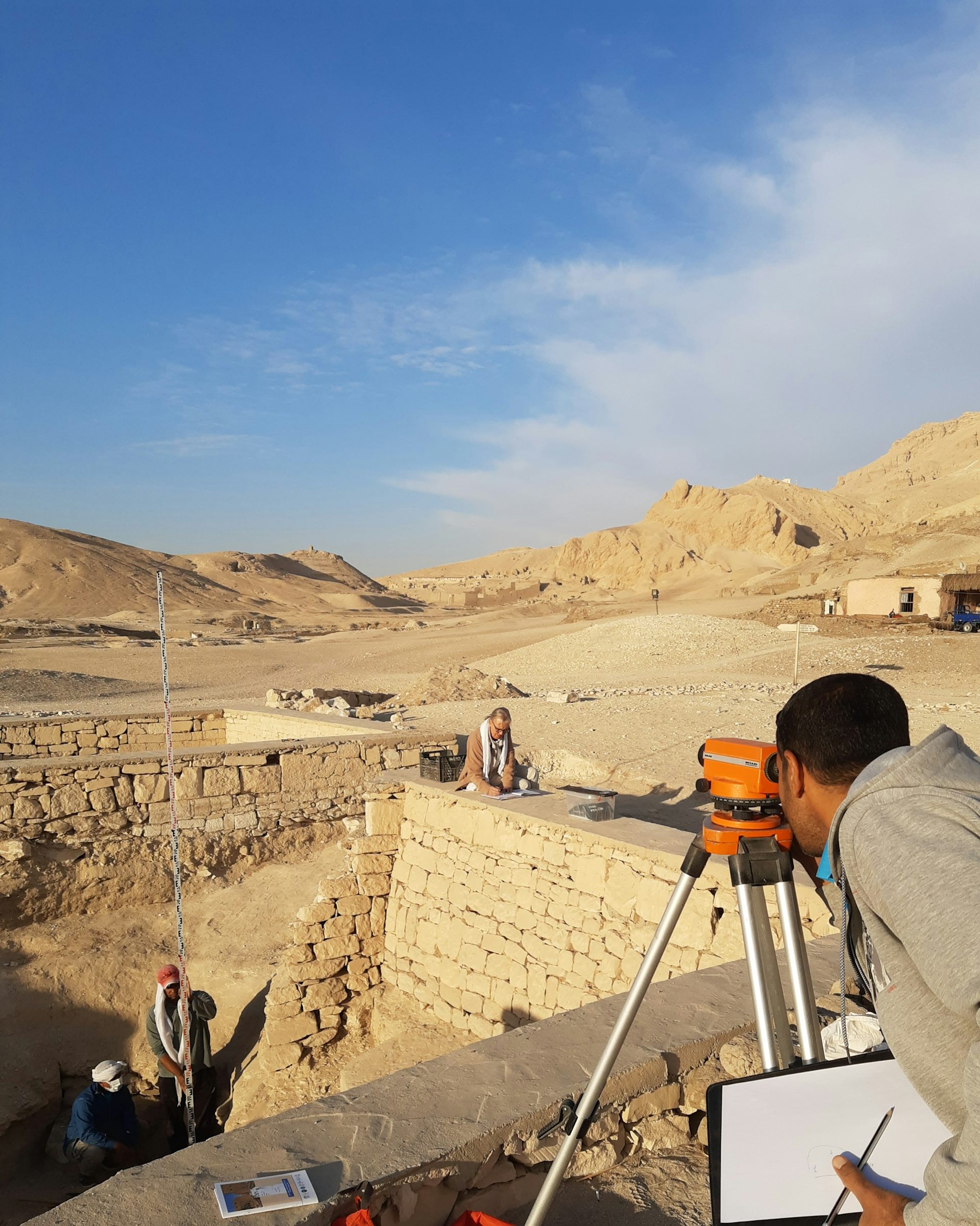 A researcher using a surveying instrument in the necropolis of Lower Sheikh ʿAbd el-Qurna.