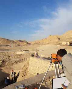 A researcher using a surveying instrument in the necropolis of Lower Sheikh ʿAbd el-Qurna.