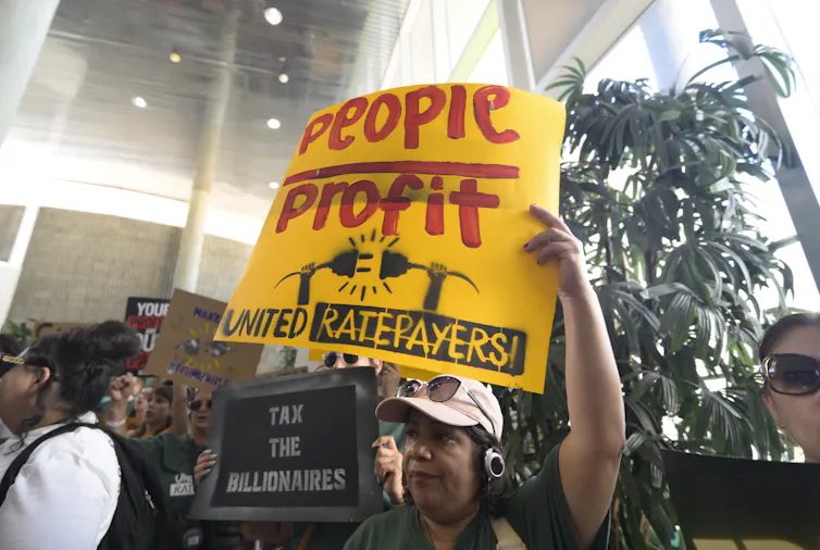 A person holds up a sign that says 'people over profit.'