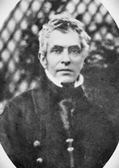 A black and white photo of a man with shaggy grey hair.