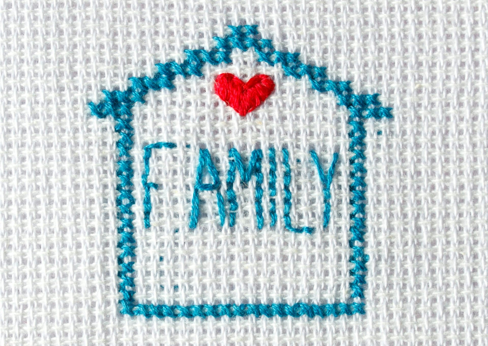 A stitched image of a blue house with the word 'FAMILY' and a red heart.