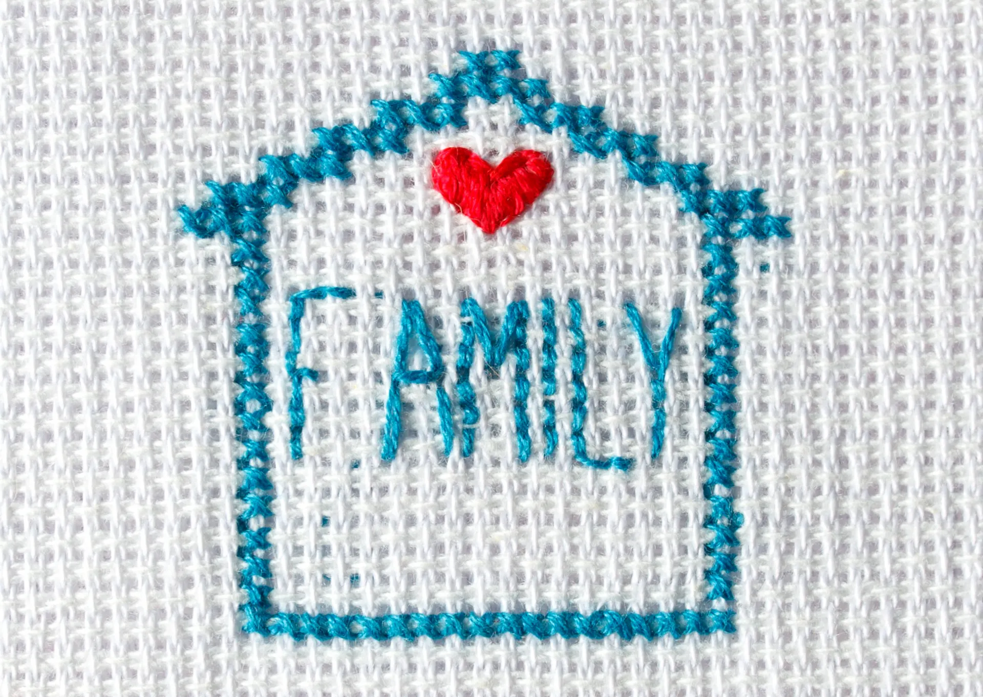 A stitched image of a blue house with the word 'FAMILY' and a red heart.