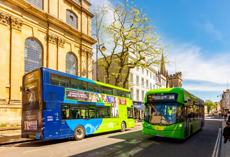 oxford city street, two buses driving down road, no cars
