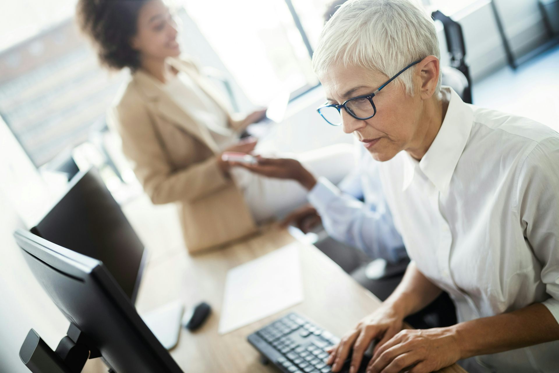 An older woman with short, white hair works on a computer
