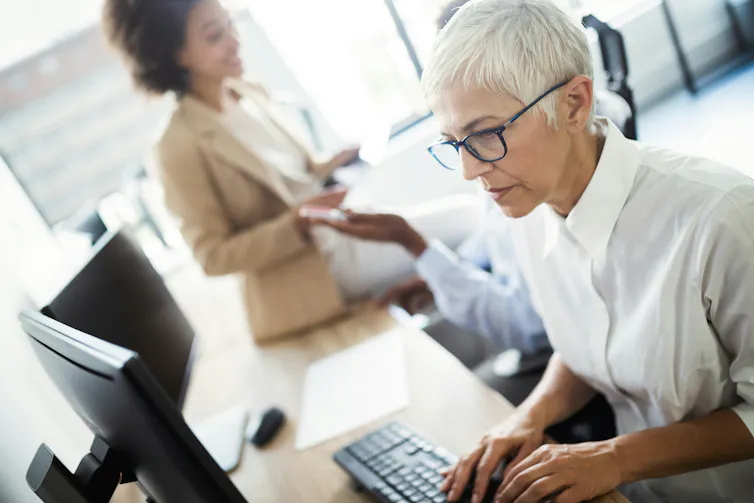 An older woman with short, white hair works on a computer