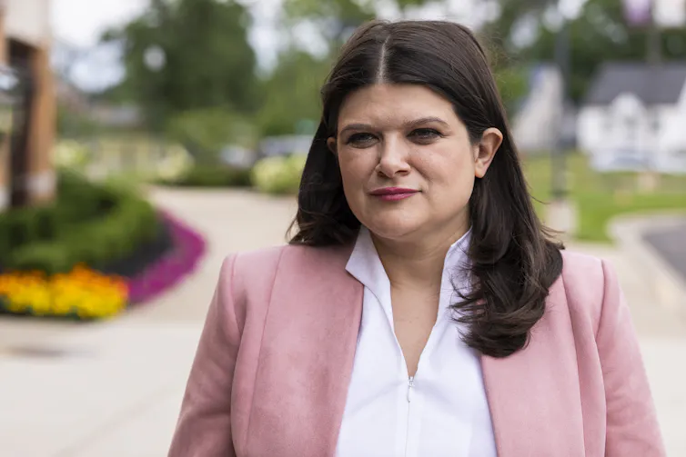 Woman in pink blazer stands