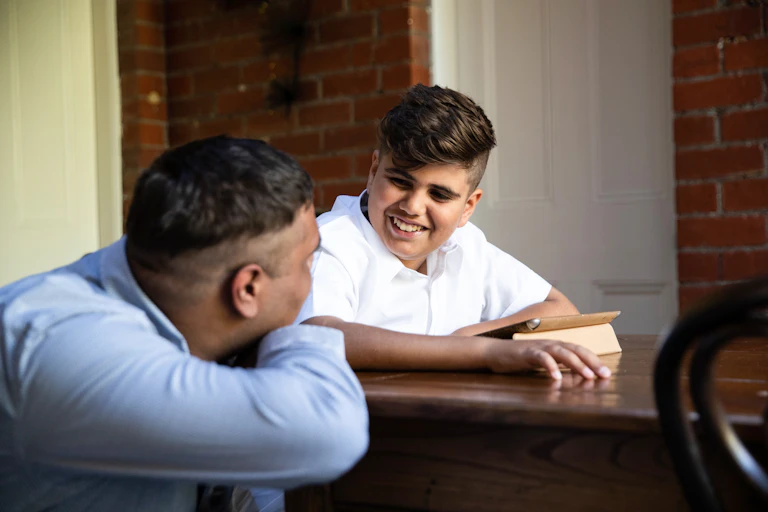 Indigenous Australian boy in school uniform smiling to his dad.