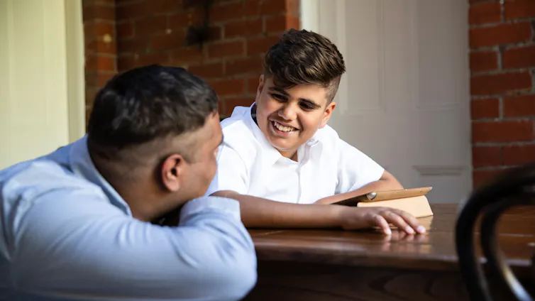 Indigenous Australian boy in school uniform smiling to his dad.