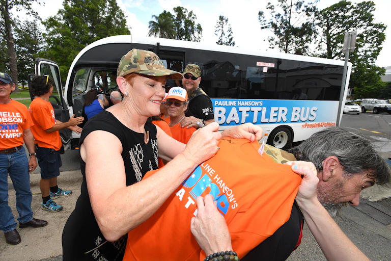 Pauline Hanson signs a One Nation T-shirt in front of her 'battler bus'.