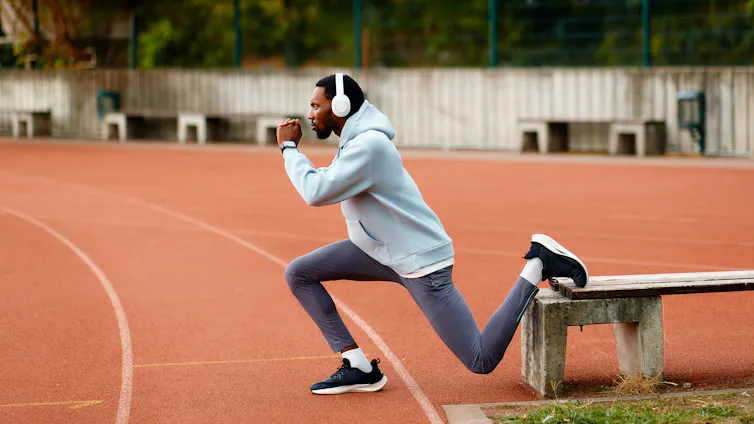 A man does a deep lunge at a training track.