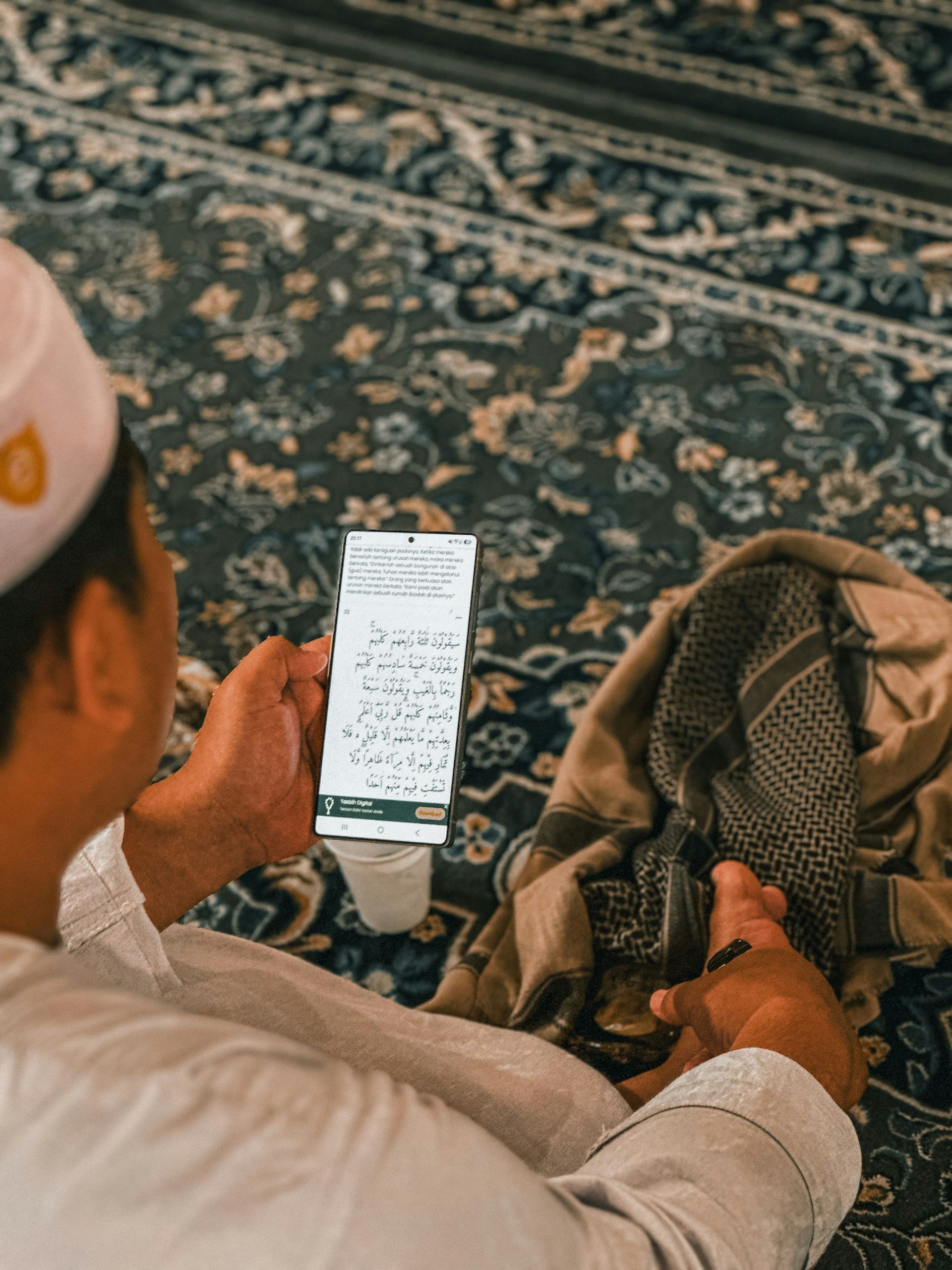 Membaca Al Quran melalui aplikasi di telepon genggam.
