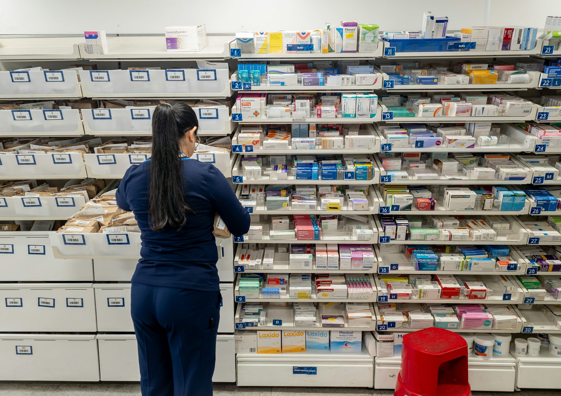 A pharmacist in front of shelves of medications.