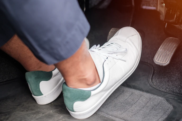 Close up of feet pressing accelerator and breaking pedal in a car