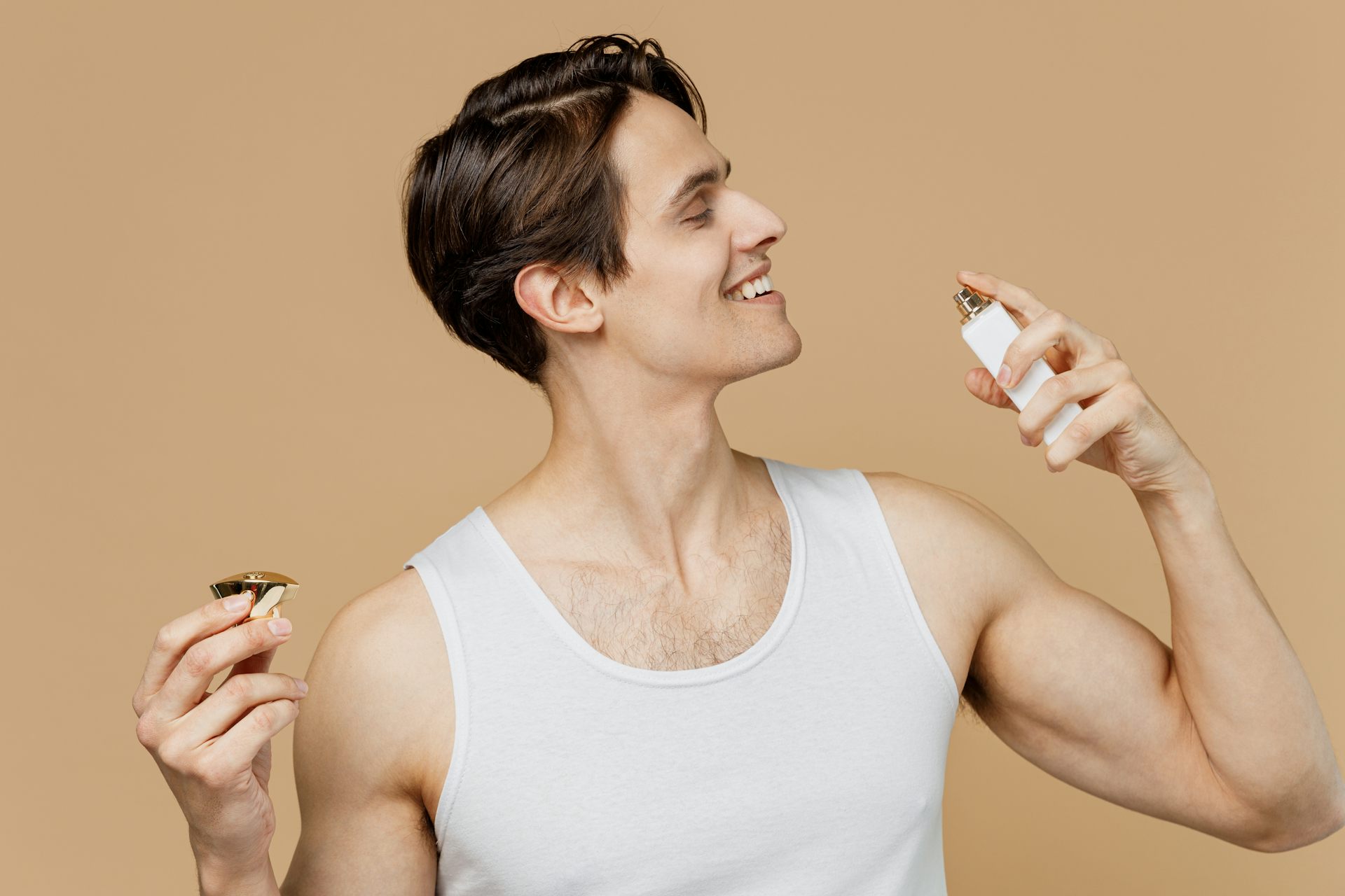 Smiling man squirts fragrance on neck