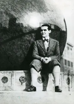 Un hombre sentado delante de un monumento en una fotografía en blanco y negro.