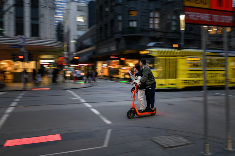A couple on an e-scooter without helmets.
