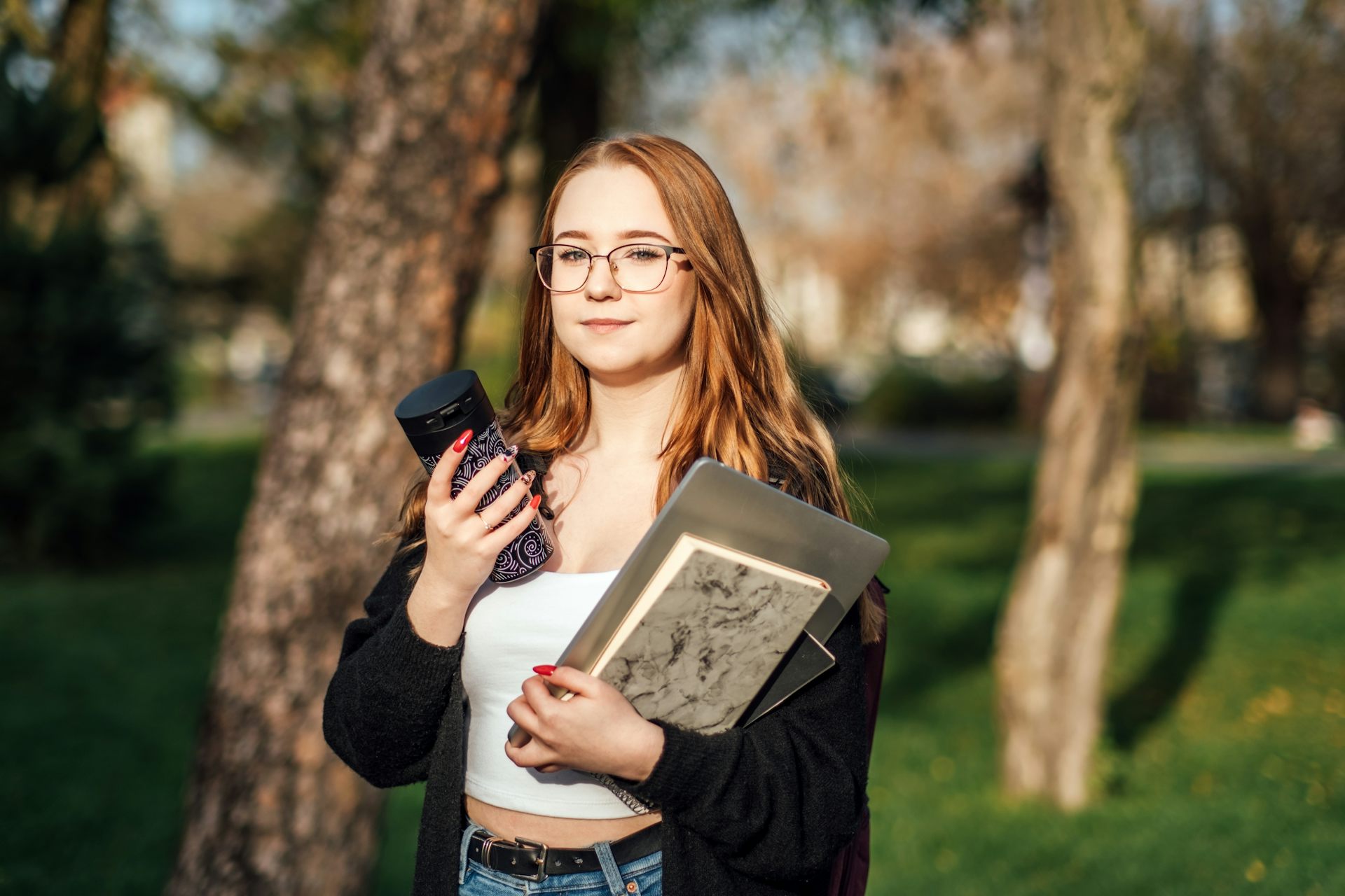 Teenager girl walking with a folder and a drinks cup.