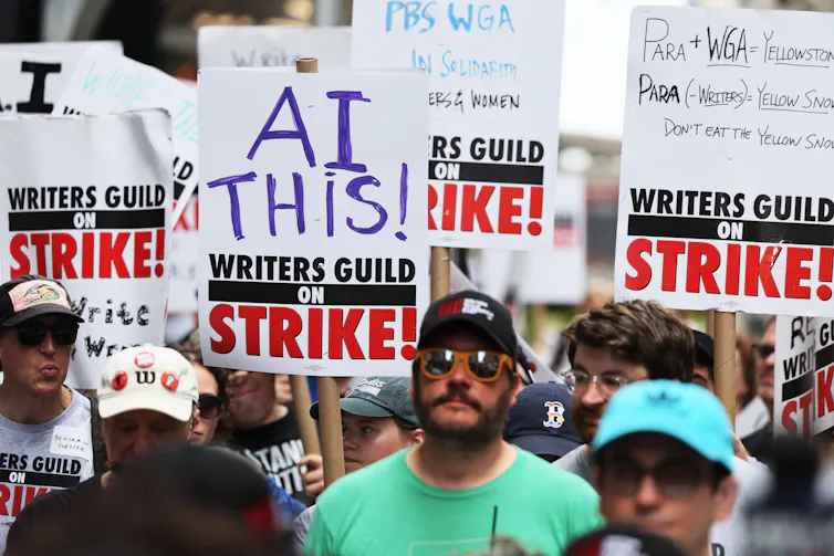 Striking members of the Writers Guild of America carry signs denouncing AI as they picket the New York office of Warner Bros. Discovery in July 2023.