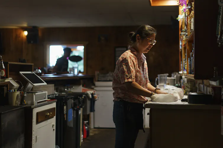 A woman in a small commercial kitchen preps a takeout order.